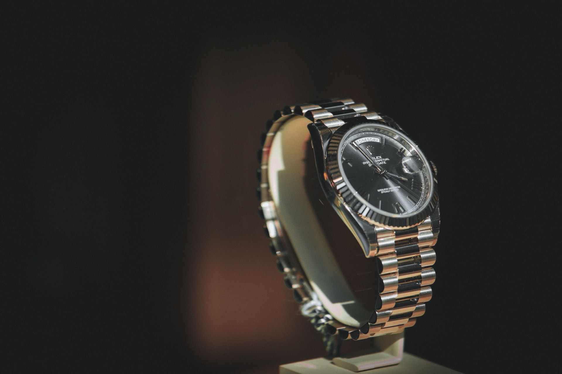 Gold Rolex Day-Date President on a display stand in warm dramatic light